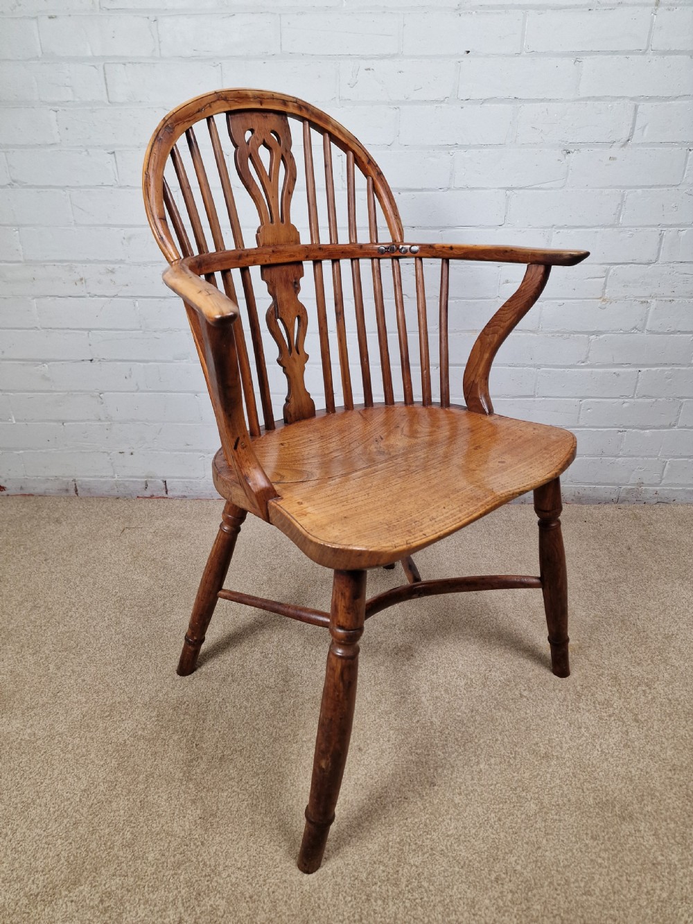 An early nineteenth-century Windsor armchair crafted from yew and elm, featuring a hoop back, pierced central splat, turned legs, and a curved crinoline stretcher. View III