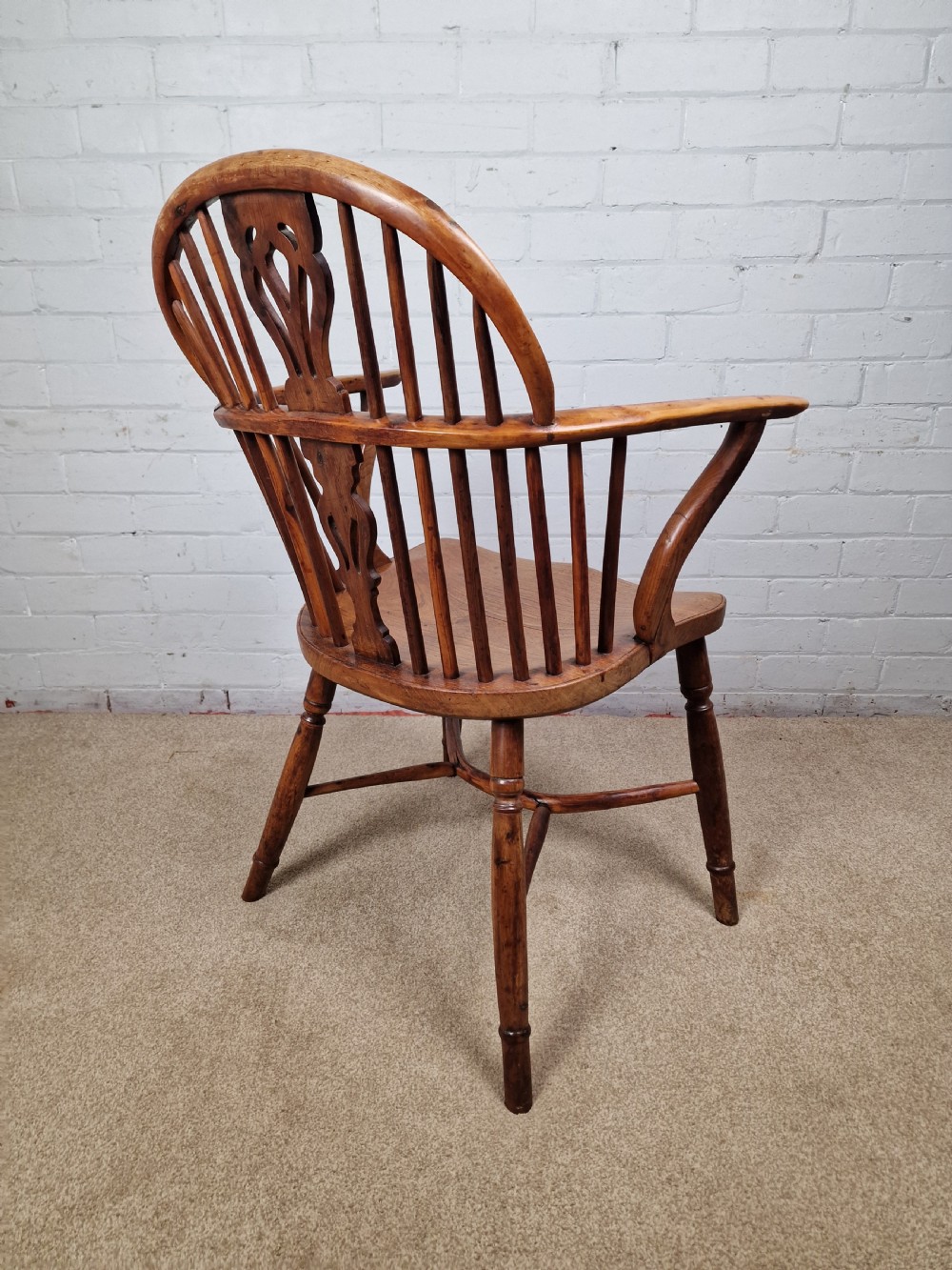 An early nineteenth-century Windsor armchair crafted from yew and elm, featuring a hoop back, pierced central splat, turned legs, and a curved crinoline stretcher. View IV