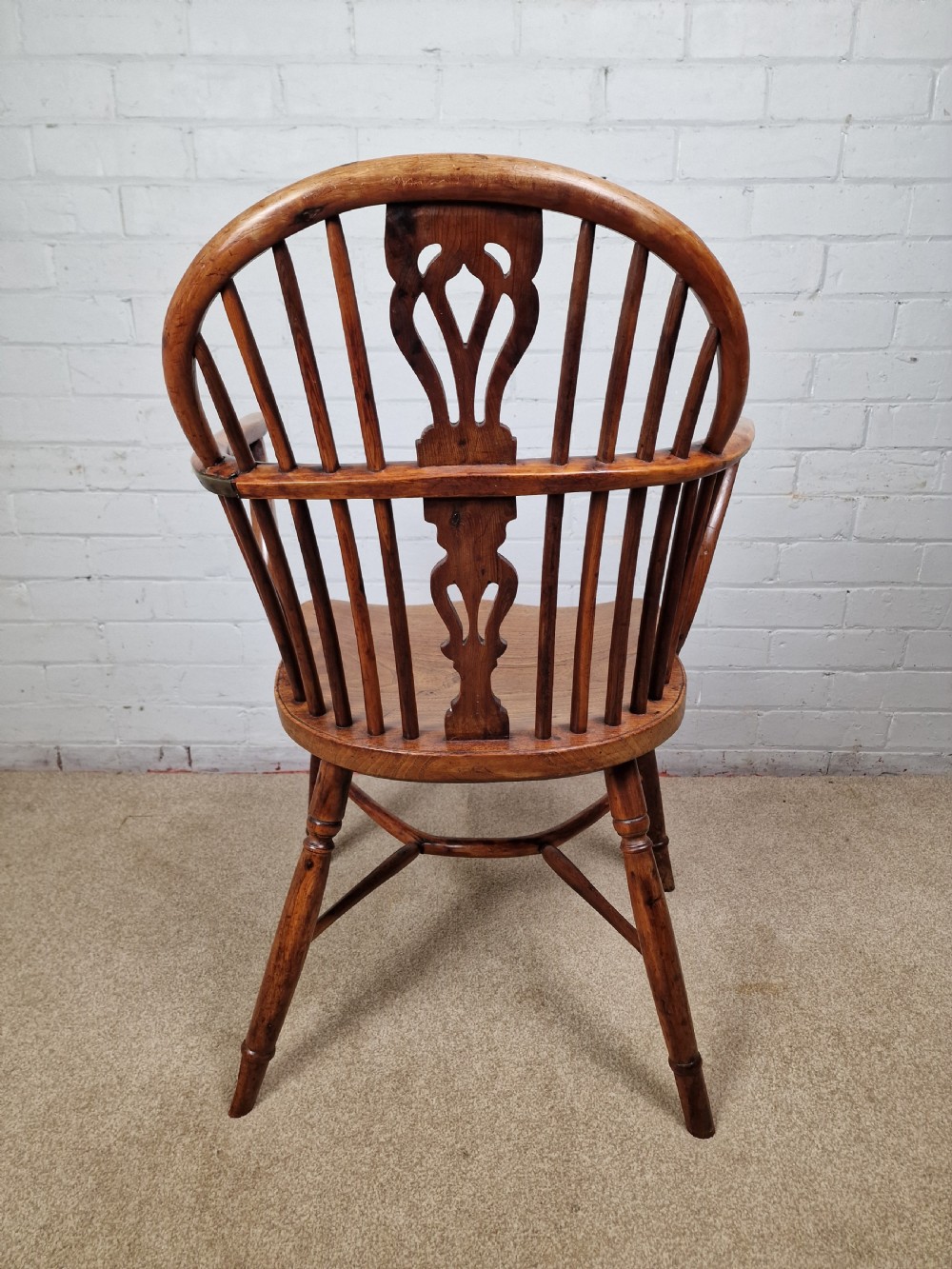 An early nineteenth-century Windsor armchair crafted from yew and elm, featuring a hoop back, pierced central splat, turned legs, and a curved crinoline stretcher. View V