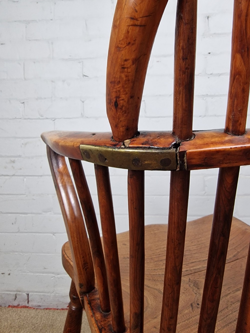 An early nineteenth-century Windsor armchair crafted from yew and elm, featuring a hoop back, pierced central splat, turned legs, and a curved crinoline stretcher. View VII