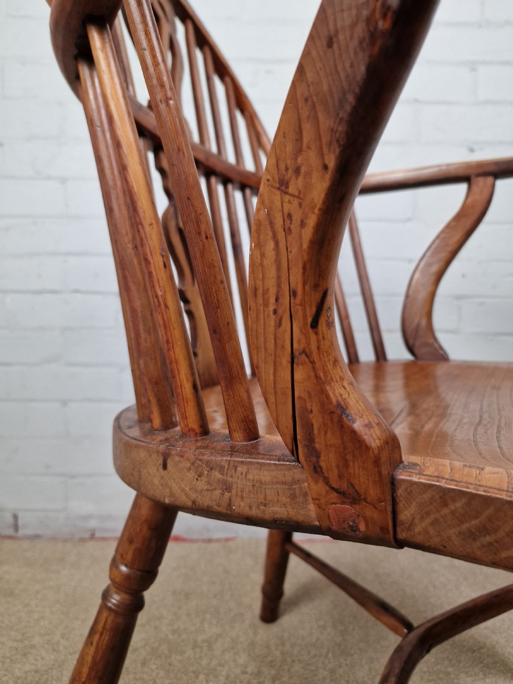 An early nineteenth-century Windsor armchair crafted from yew and elm, featuring a hoop back, pierced central splat, turned legs, and a curved crinoline stretcher. View X