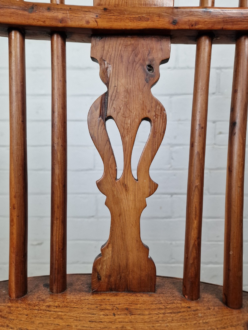 An early nineteenth-century Windsor armchair crafted from yew and elm, featuring a hoop back, pierced central splat, turned legs, and a curved crinoline stretcher. View XII