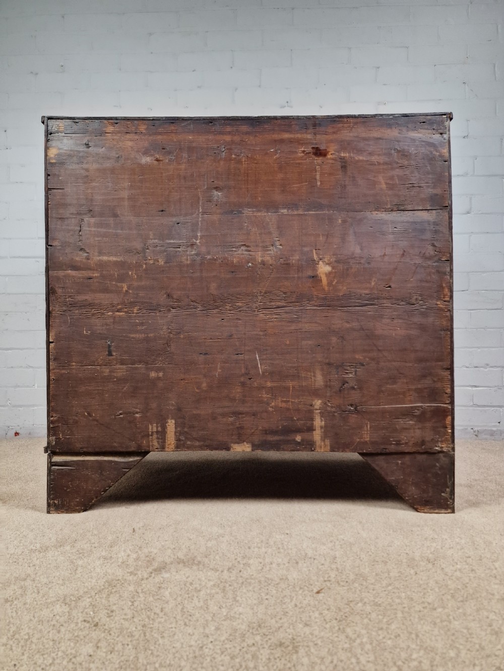 An antique Georgian oak chest of drawers featuring a two-over-three drawer configuration with oval brass drop handles and bracket feet. View VI