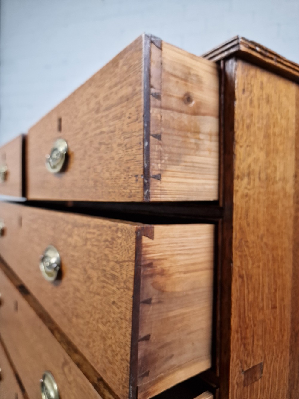 An antique Georgian oak chest of drawers featuring a two-over-three drawer configuration with oval brass drop handles and bracket feet. View VIII