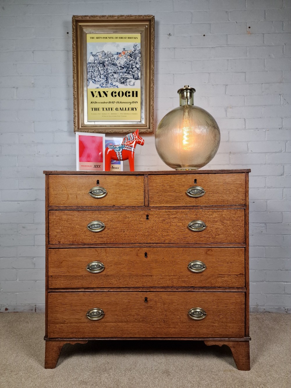 An antique Georgian oak chest of drawers featuring a two-over-three drawer configuration with oval brass drop handles and bracket feet. View XI