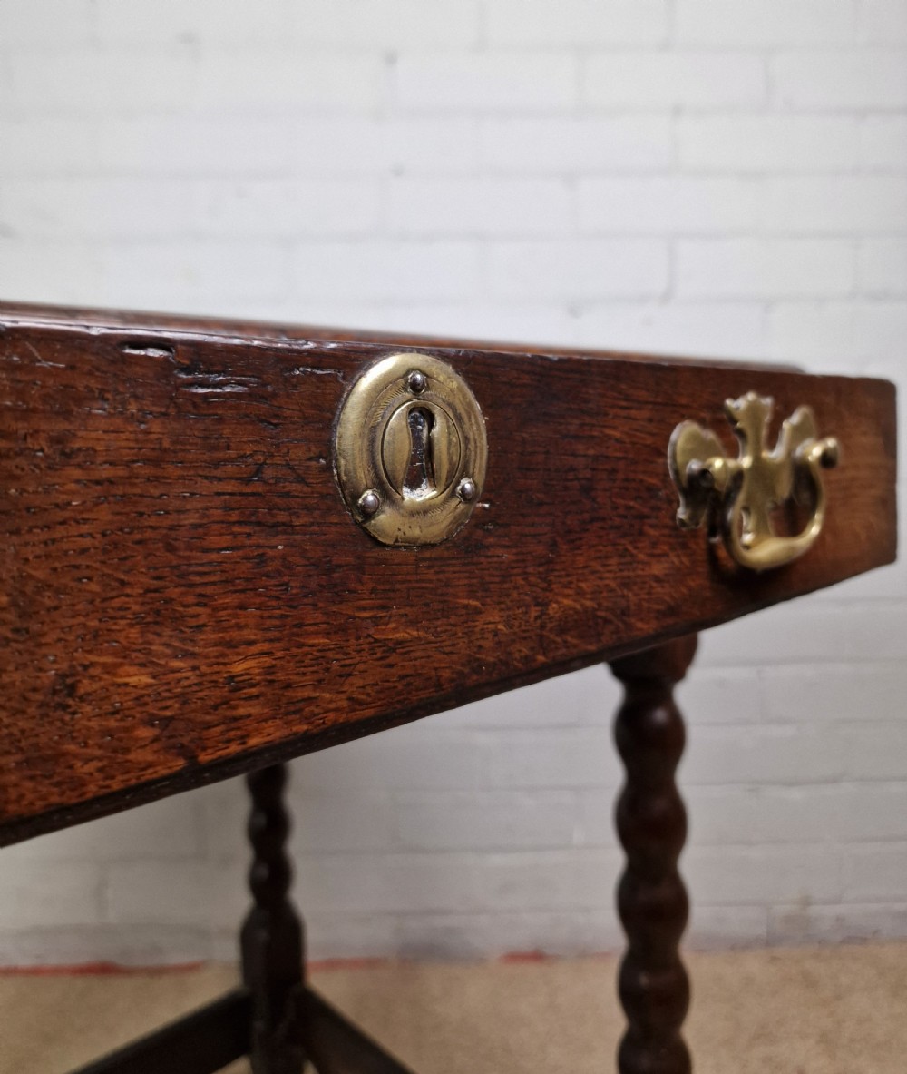 An 18th-century dark oak side table featuring four bobbin-turned legs, a square top, a single drawer with brass handles, and a box stretcher. View VIII