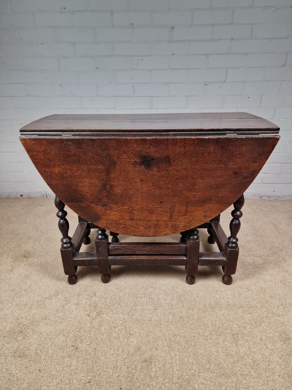 An 18th-century dark oak gateleg table featuring folded drop leaves, turned legs, and lower stretchers. View XII