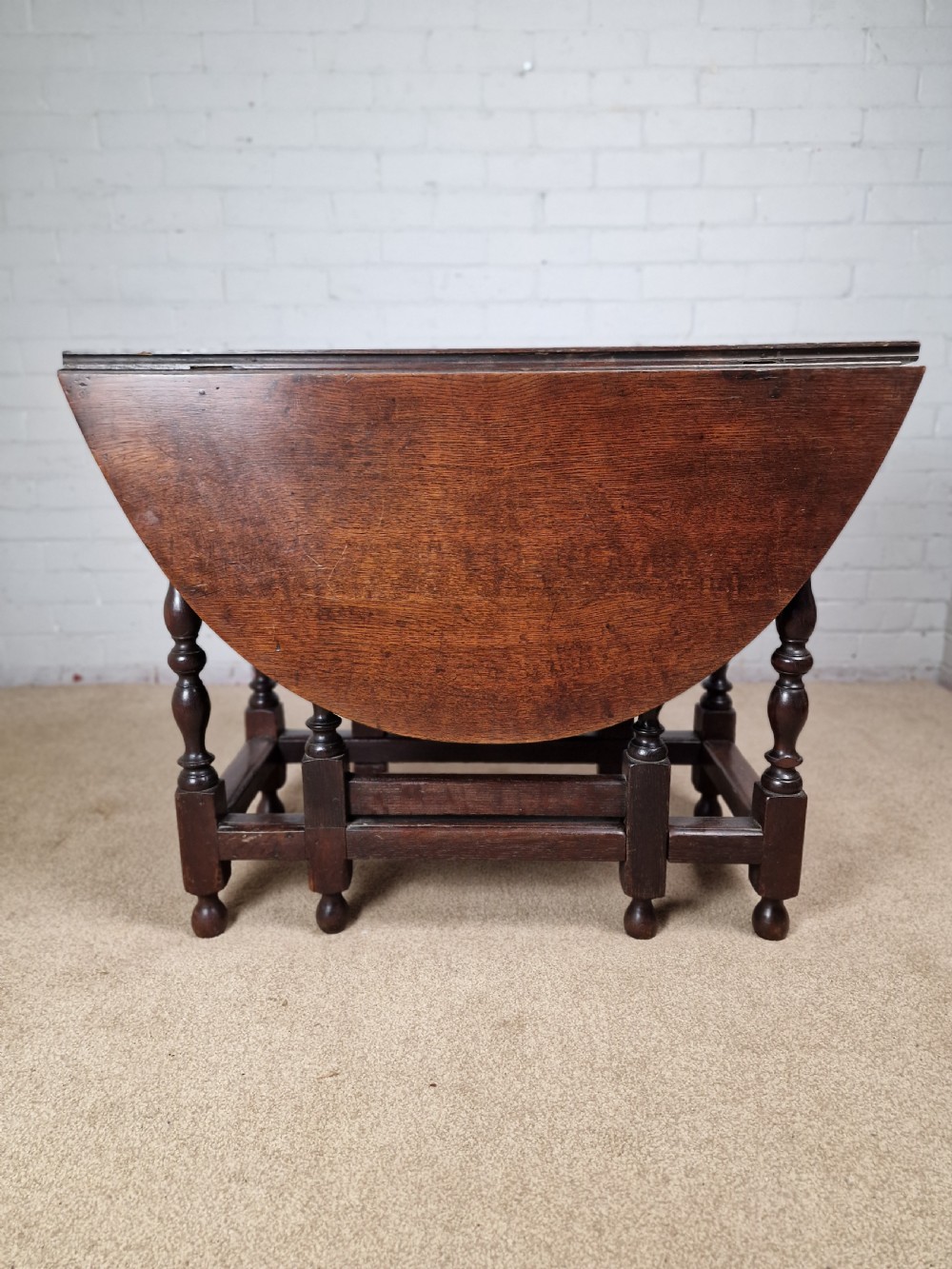 An 18th-century dark oak gateleg table featuring folded drop leaves, turned legs, and lower stretchers. View IV