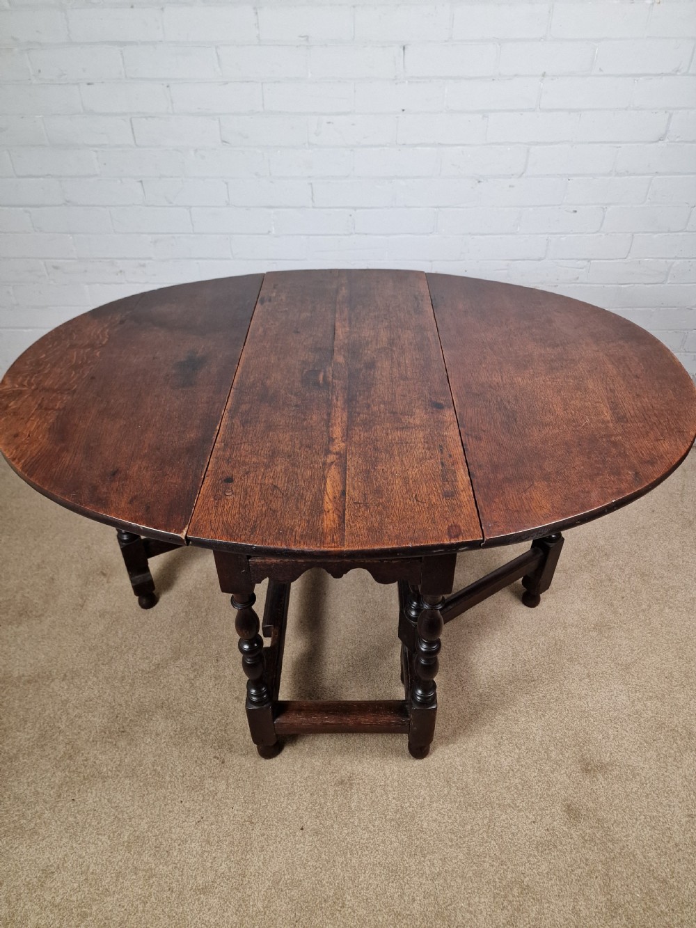 An 18th-century dark oak gateleg table featuring folded drop leaves, turned legs, and lower stretchers. View VIII