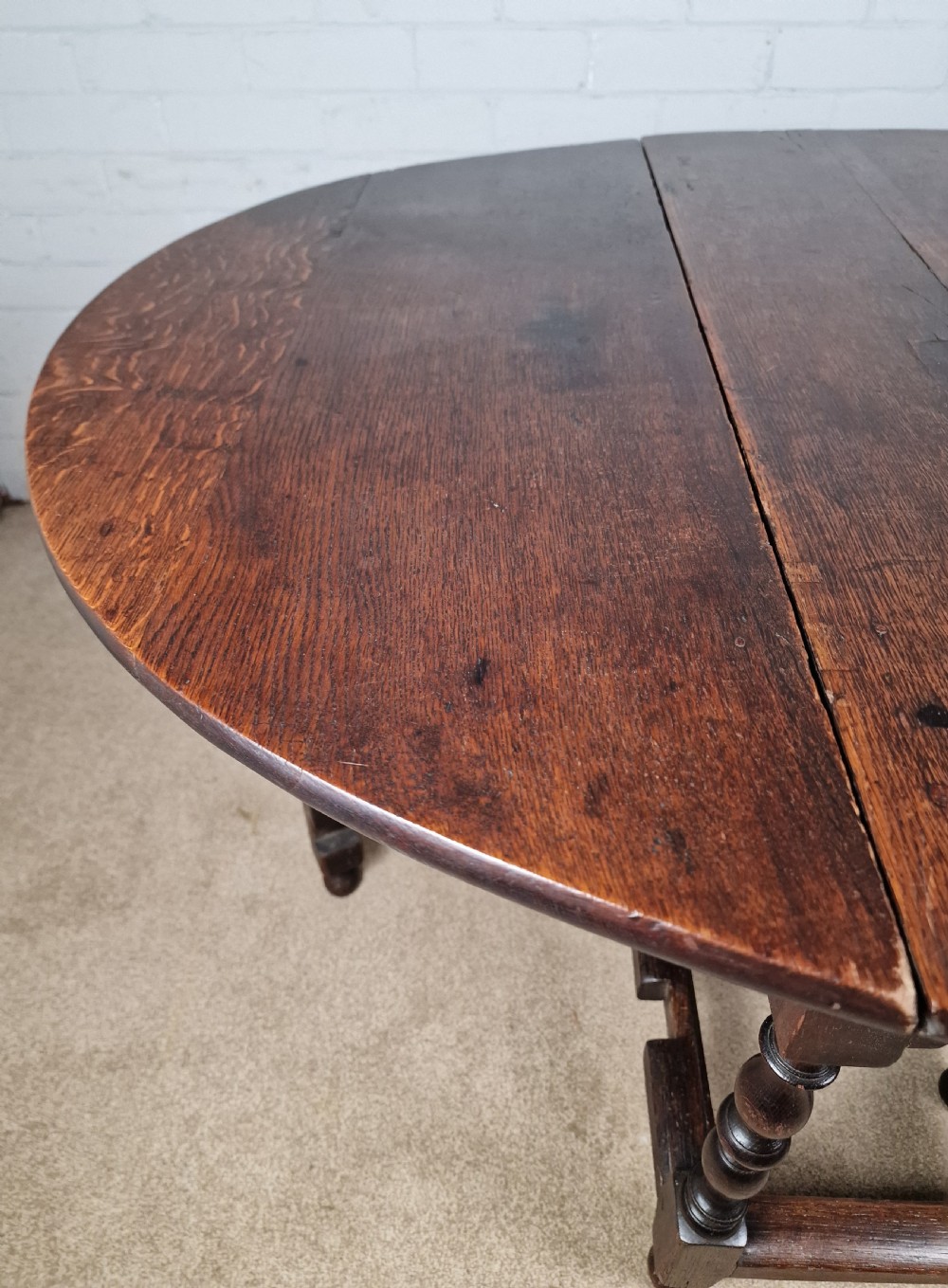 An 18th-century dark oak gateleg table featuring folded drop leaves, turned legs, and lower stretchers. View X