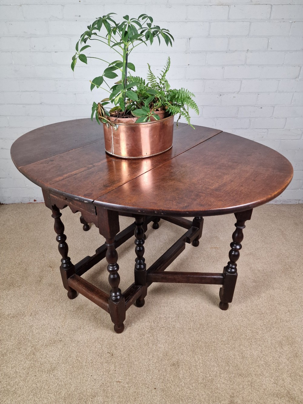 An 18th-century dark oak gateleg table featuring folded drop leaves, turned legs, and lower stretchers. View XIII