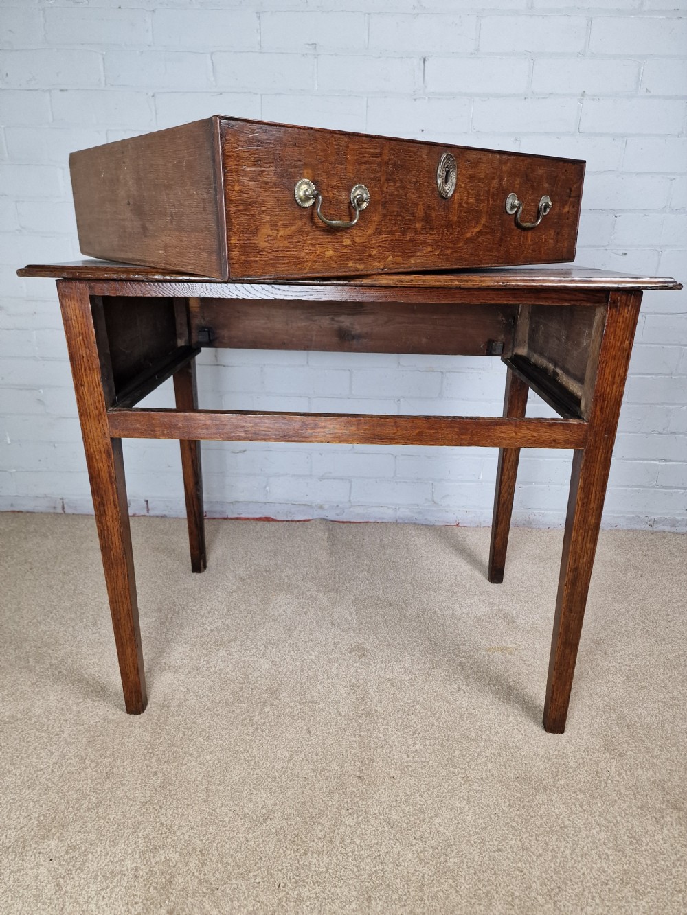 An 18th-century antique oak lowboy side table featuring a single wide drawer with brass handles and square tapered legs. View VIII