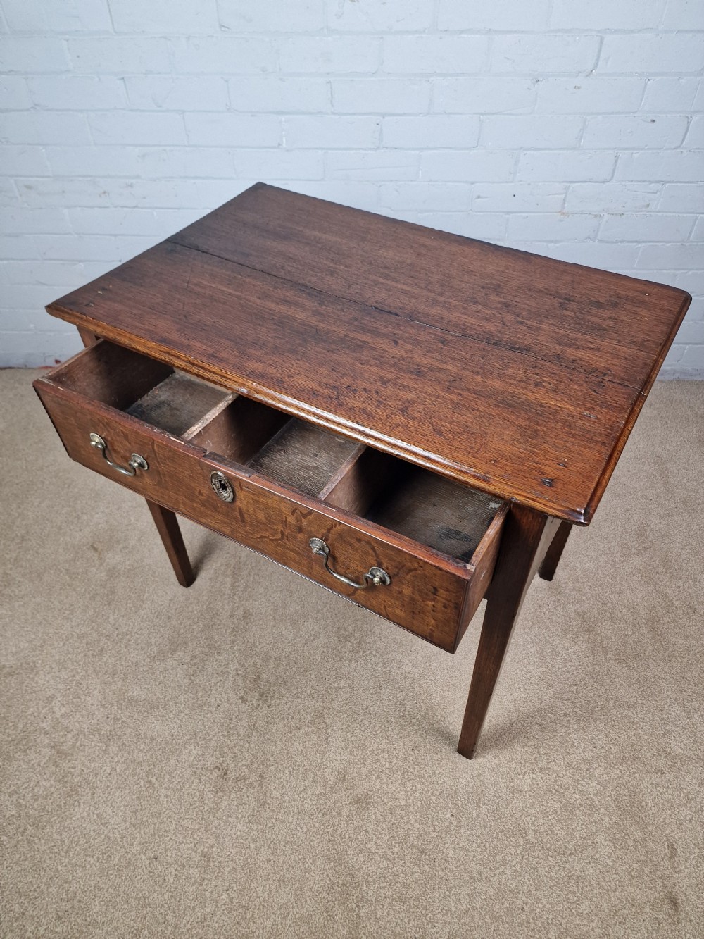 An 18th-century antique oak lowboy side table featuring a single wide drawer with brass handles and square tapered legs. View XII