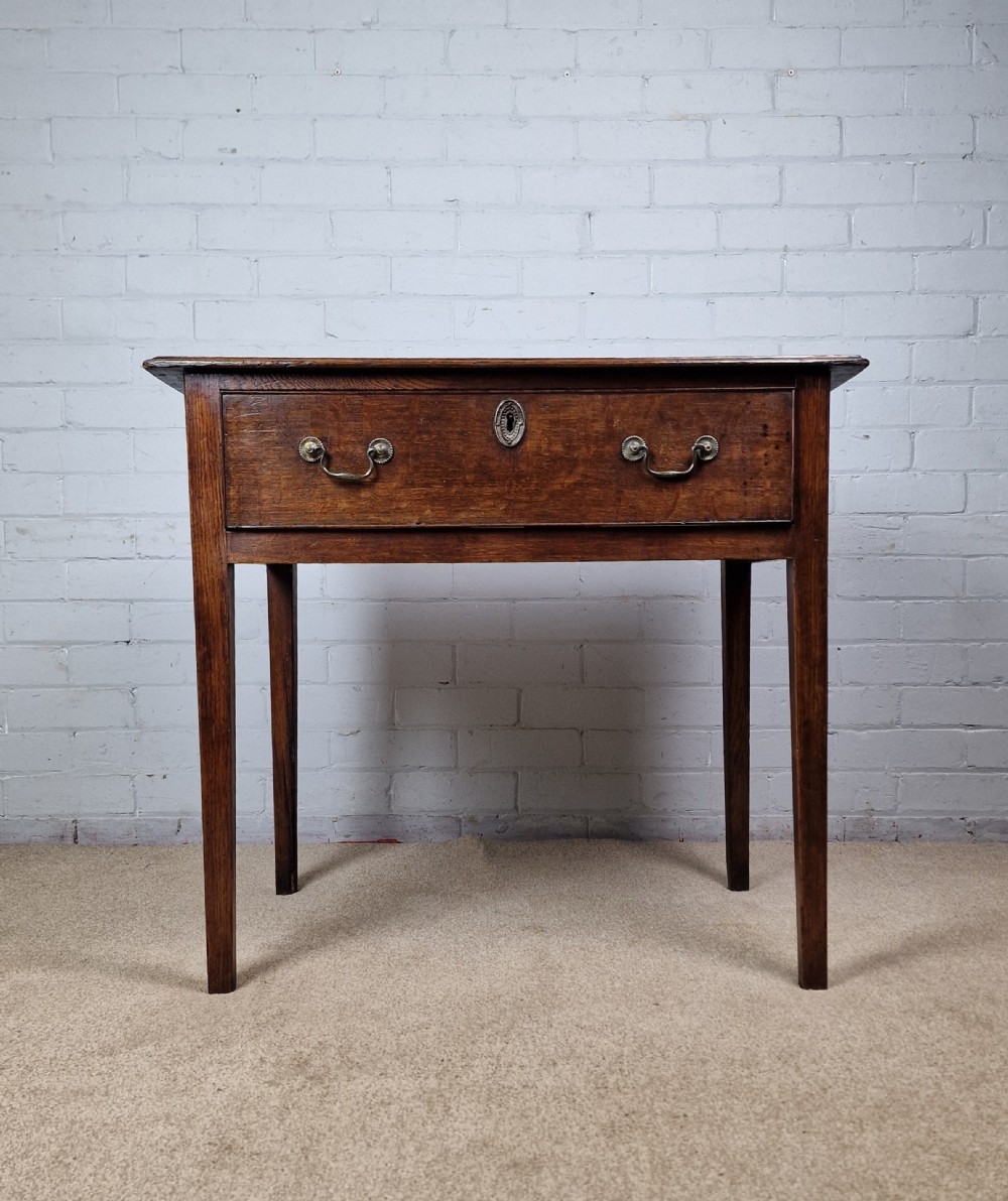 An 18th-century antique oak lowboy side table featuring a single wide drawer with brass handles and square tapered legs. View XIII