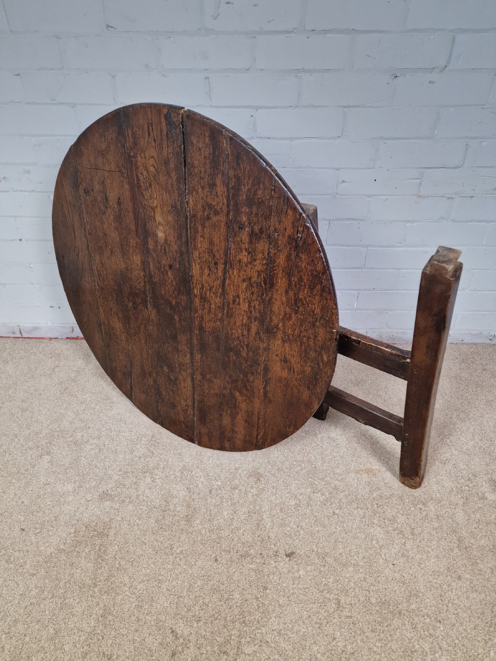 A circular dark oak George III coaching table featuring a planked top and a folding wooden base structure. View VI