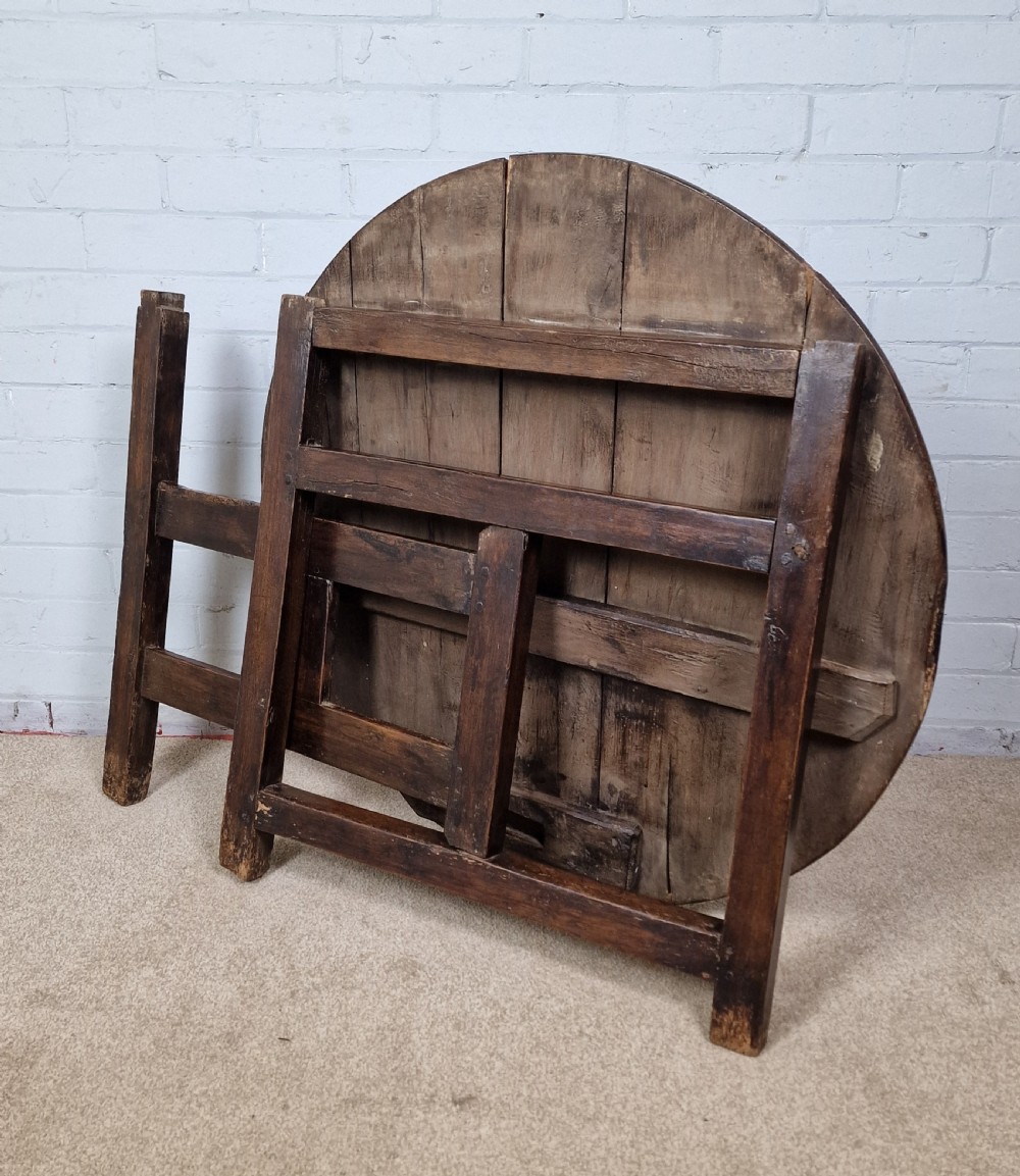 A circular dark oak George III coaching table featuring a planked top and a folding wooden base structure. View VII