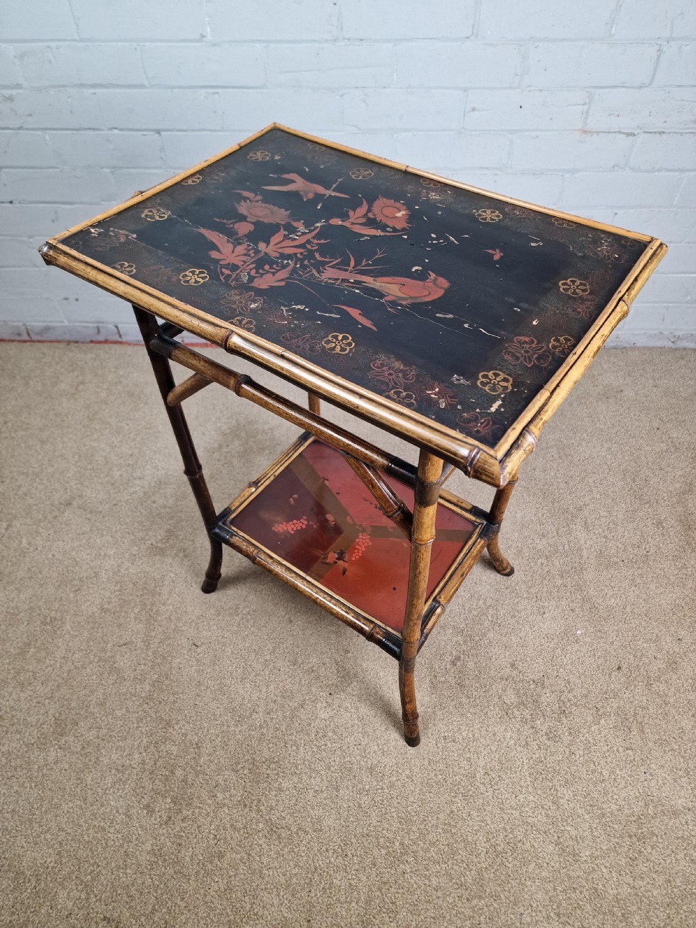 A 19th-century Aesthetic Movement side table crafted from bamboo with a dark lacquered top panel featuring floral hand-painted details and an undertier. View II