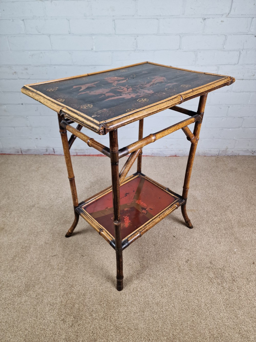 A 19th-century Aesthetic Movement side table crafted from bamboo with a dark lacquered top panel featuring floral hand-painted details and an undertier.