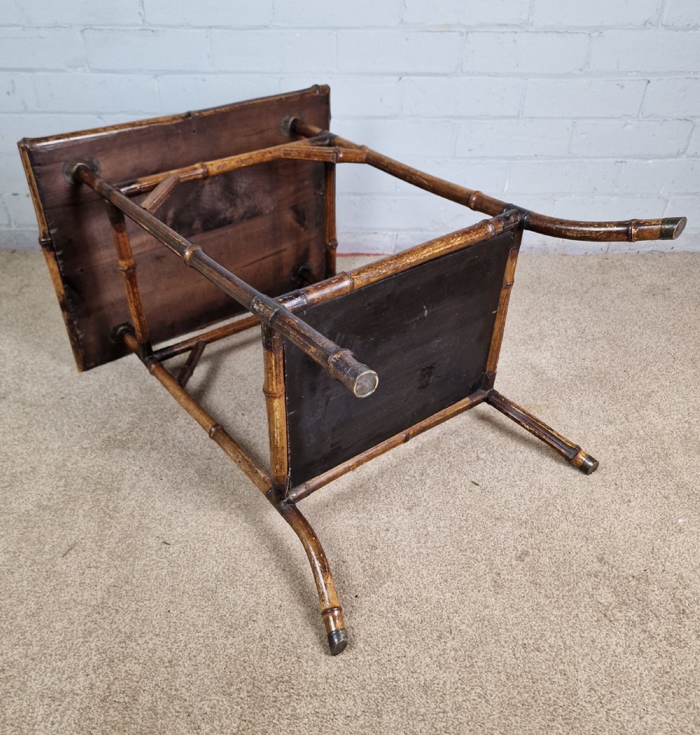 A 19th-century Aesthetic Movement side table crafted from bamboo with a dark lacquered top panel featuring floral hand-painted details and an undertier. View X