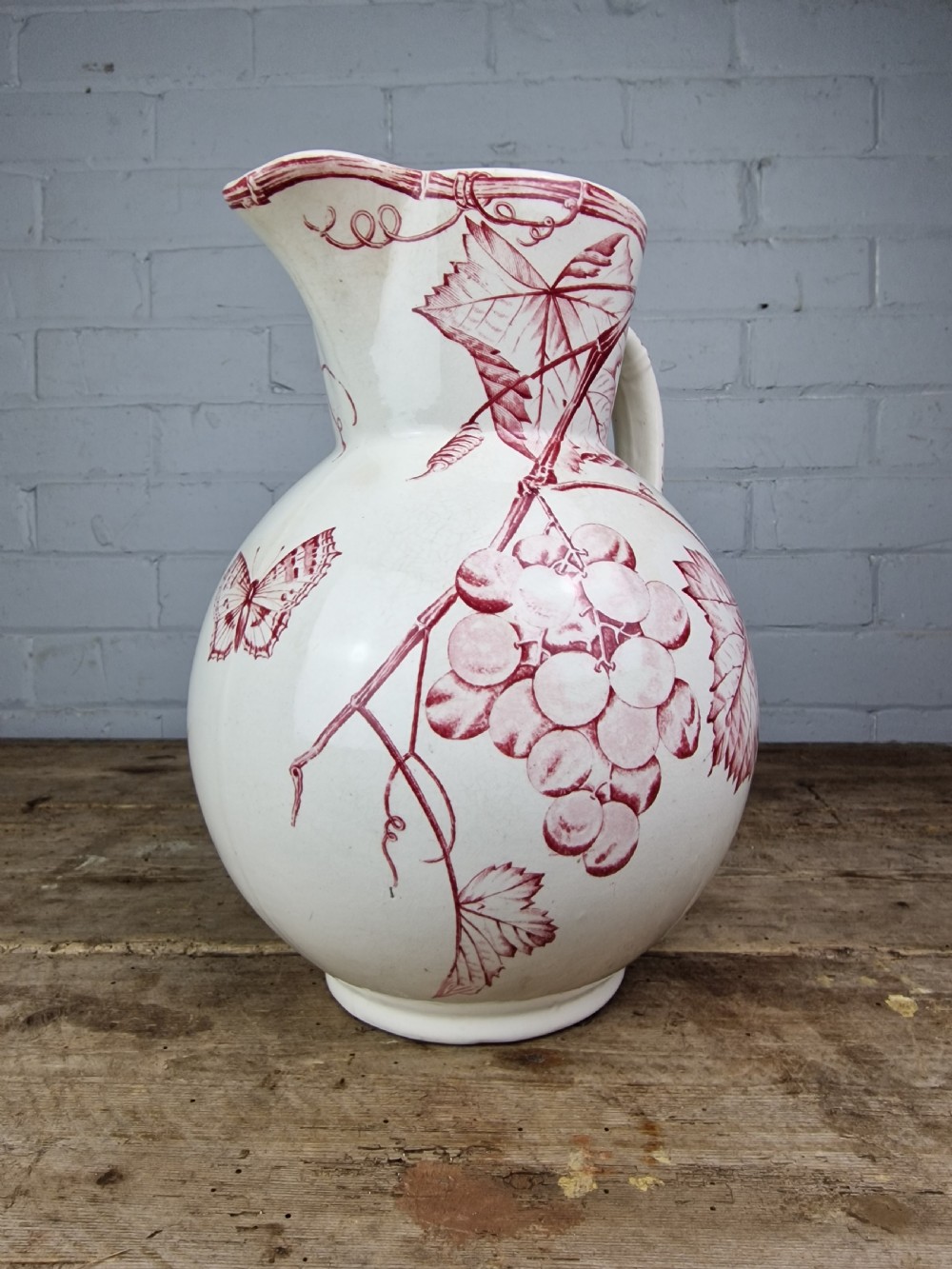 A Victorian cream ceramic jug decorated with a red transferware pattern of grapes and vine leaves. View II