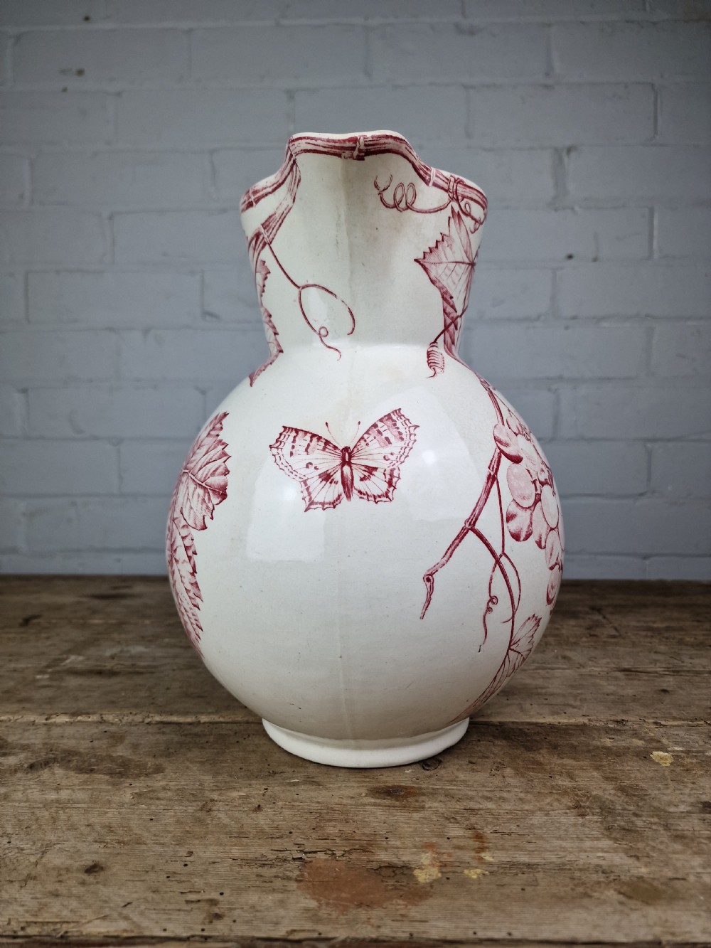 A Victorian cream ceramic jug decorated with a red transferware pattern of grapes and vine leaves. View III