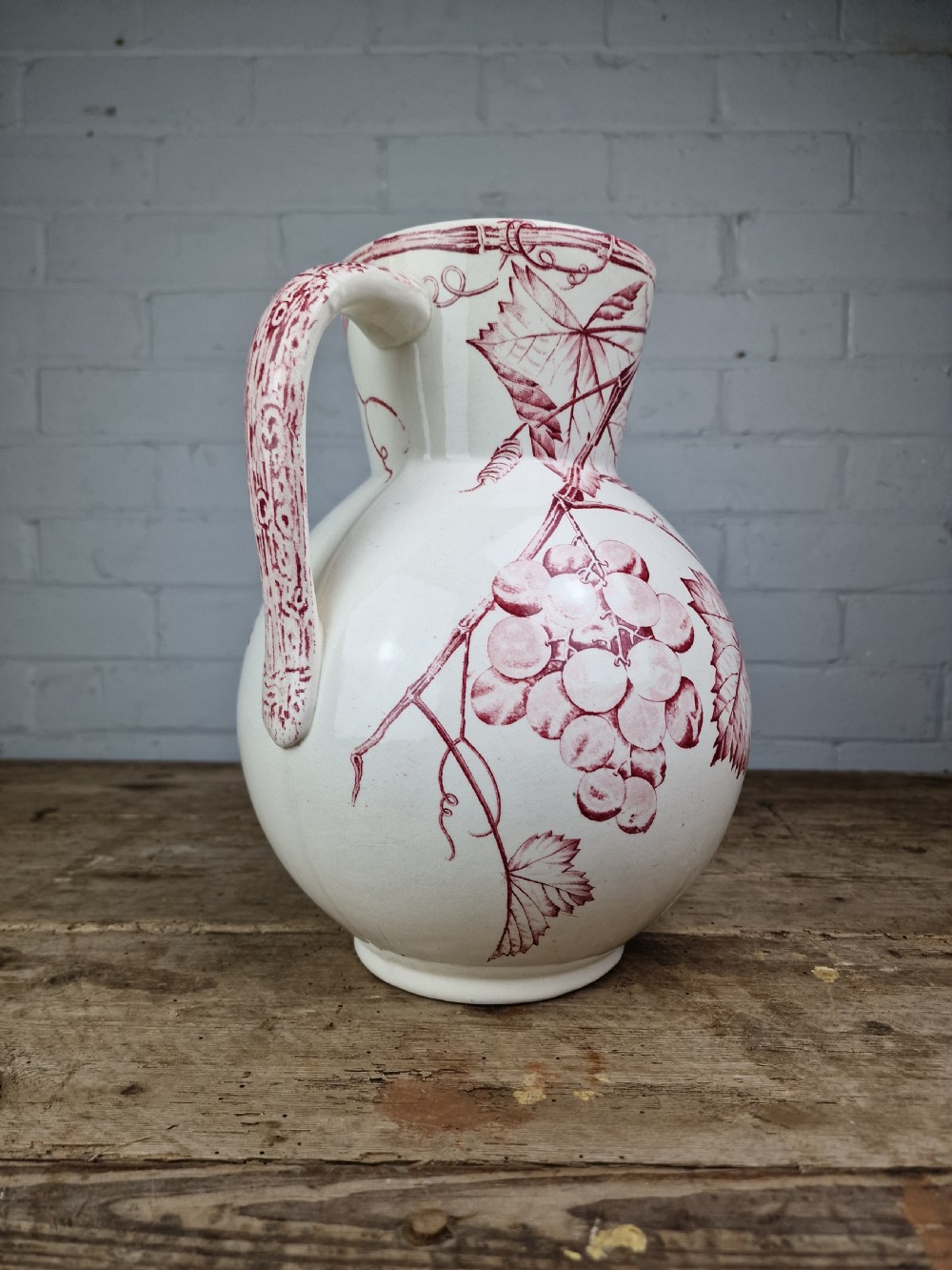 A Victorian cream ceramic jug decorated with a red transferware pattern of grapes and vine leaves. View VI