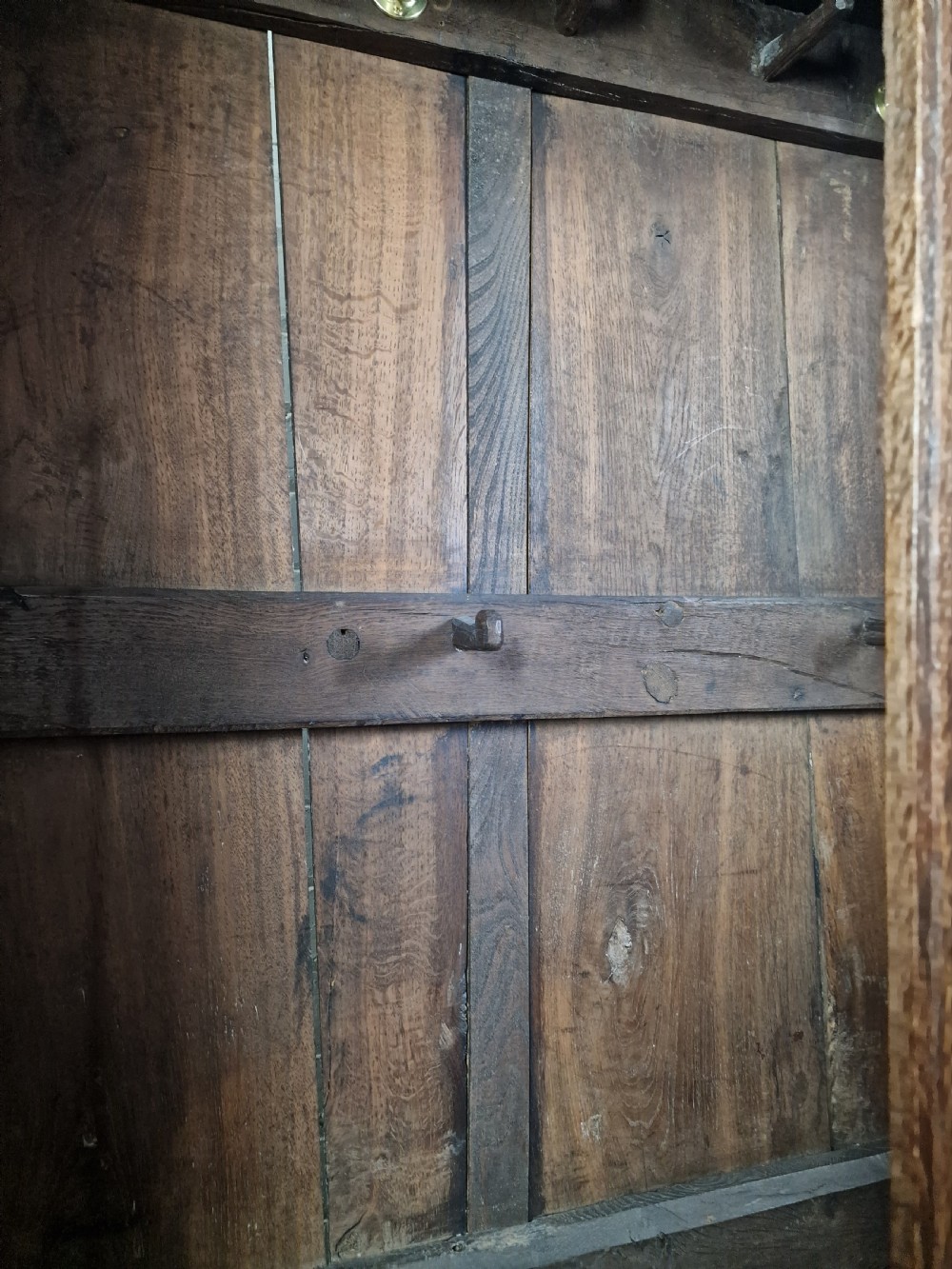 A tall Georgian dark oak livery cupboard featuring arched panel doors, iron hinges, three lower panels, and two drawers at the base. View III
