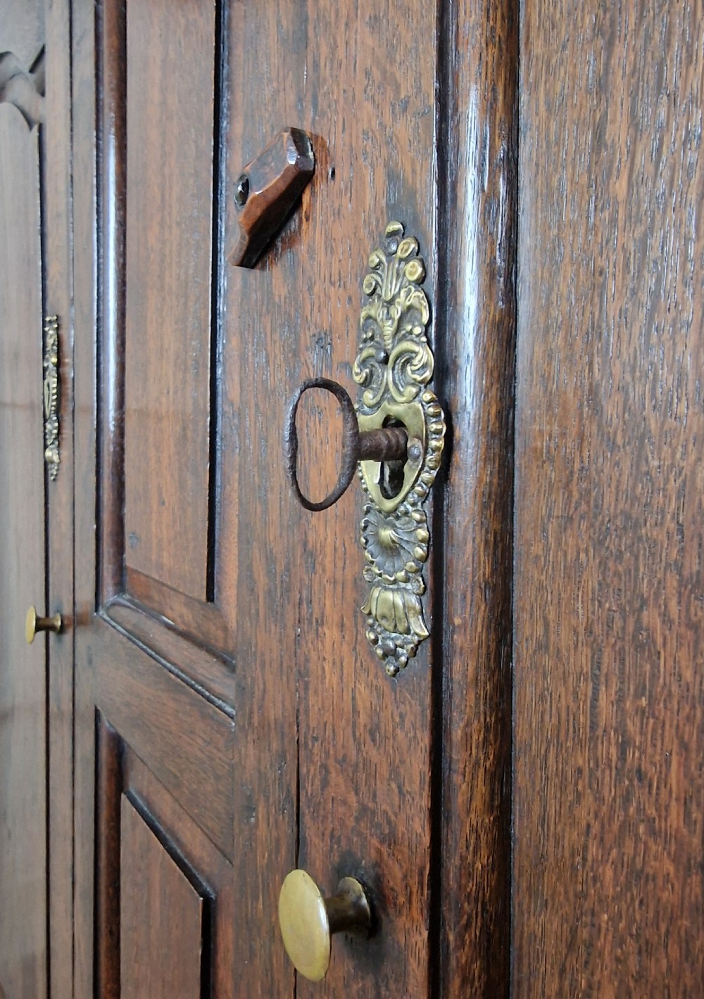 A tall Georgian dark oak livery cupboard featuring arched panel doors, iron hinges, three lower panels, and two drawers at the base. View X