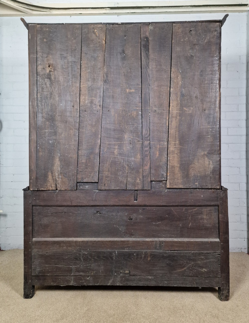 A tall Georgian dark oak livery cupboard featuring arched panel doors, iron hinges, three lower panels, and two drawers at the base. View XIV