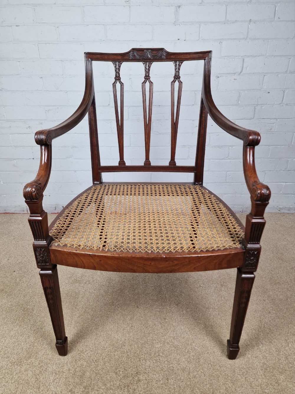 A Georgian mahogany open armchair featuring carved splats, curved arms, tapered fluted front legs, and a padded blue velvet cushion seat. View II