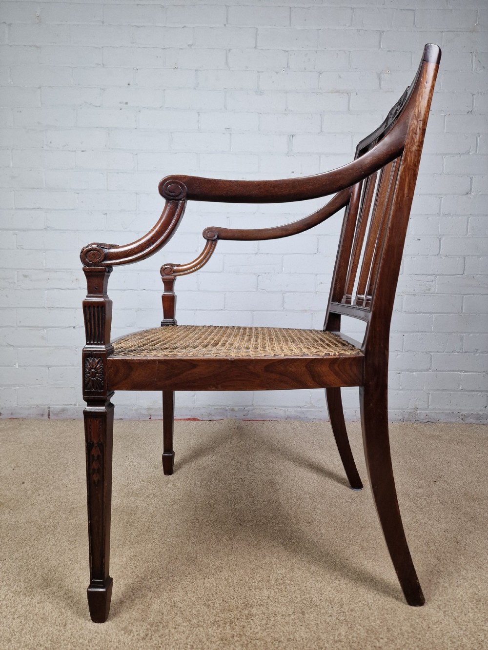 A Georgian mahogany open armchair featuring carved splats, curved arms, tapered fluted front legs, and a padded blue velvet cushion seat. View III