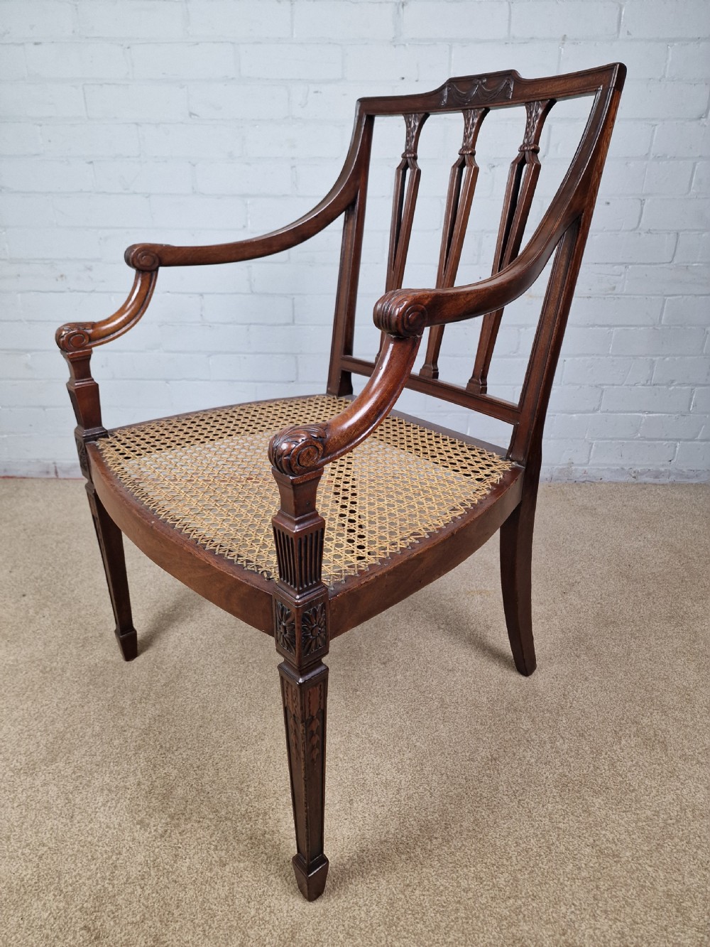 A Georgian mahogany open armchair featuring carved splats, curved arms, tapered fluted front legs, and a padded blue velvet cushion seat. View IV