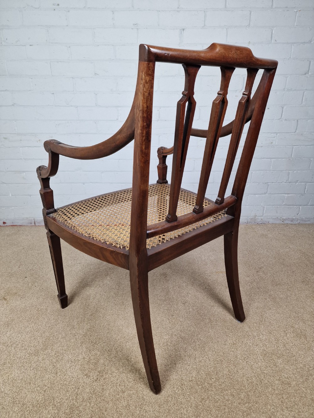 A Georgian mahogany open armchair featuring carved splats, curved arms, tapered fluted front legs, and a padded blue velvet cushion seat. View V