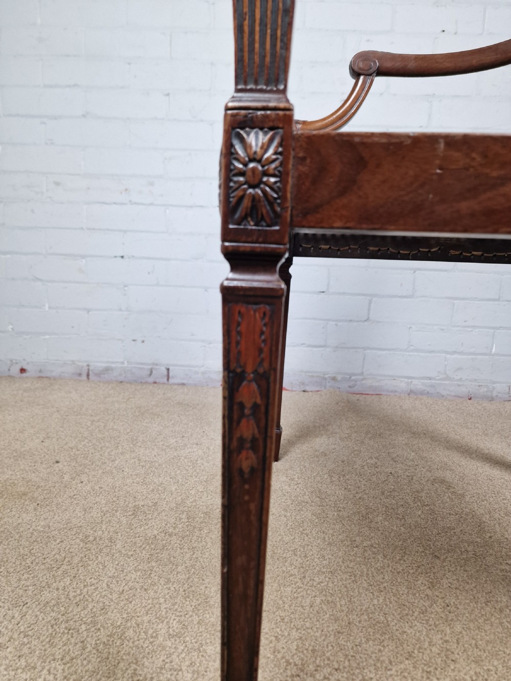 A Georgian mahogany open armchair featuring carved splats, curved arms, tapered fluted front legs, and a padded blue velvet cushion seat. View VI