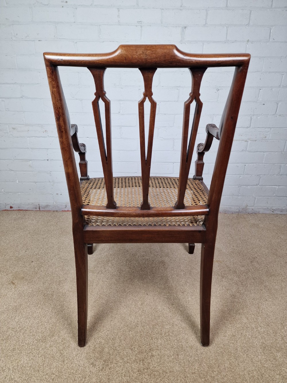 A Georgian mahogany open armchair featuring carved splats, curved arms, tapered fluted front legs, and a padded blue velvet cushion seat. View VII