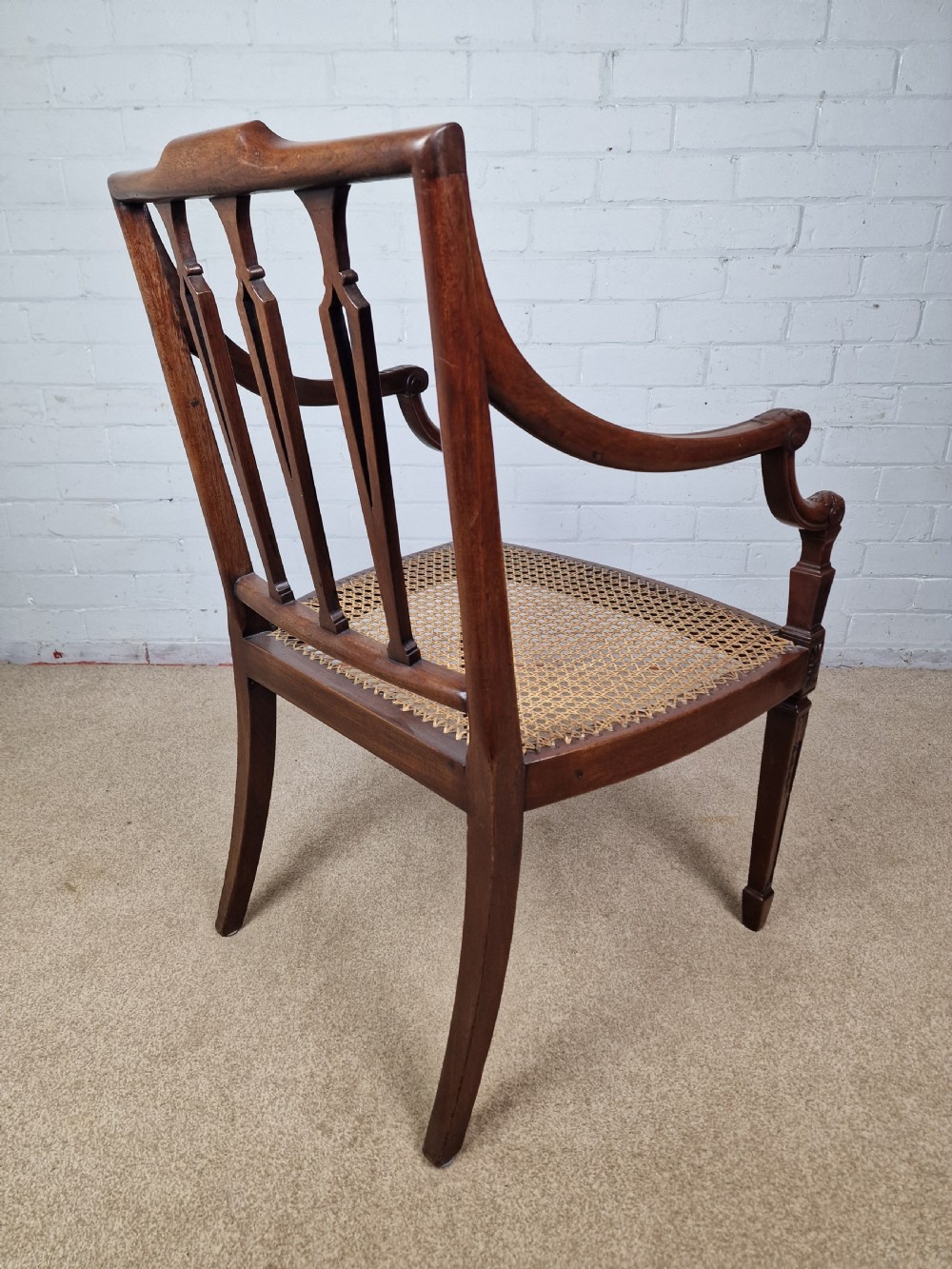 A Georgian mahogany open armchair featuring carved splats, curved arms, tapered fluted front legs, and a padded blue velvet cushion seat. View VIII