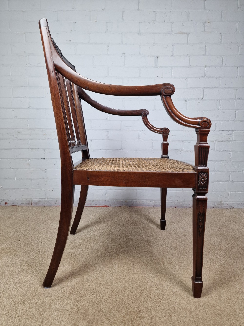 A Georgian mahogany open armchair featuring carved splats, curved arms, tapered fluted front legs, and a padded blue velvet cushion seat. View IX