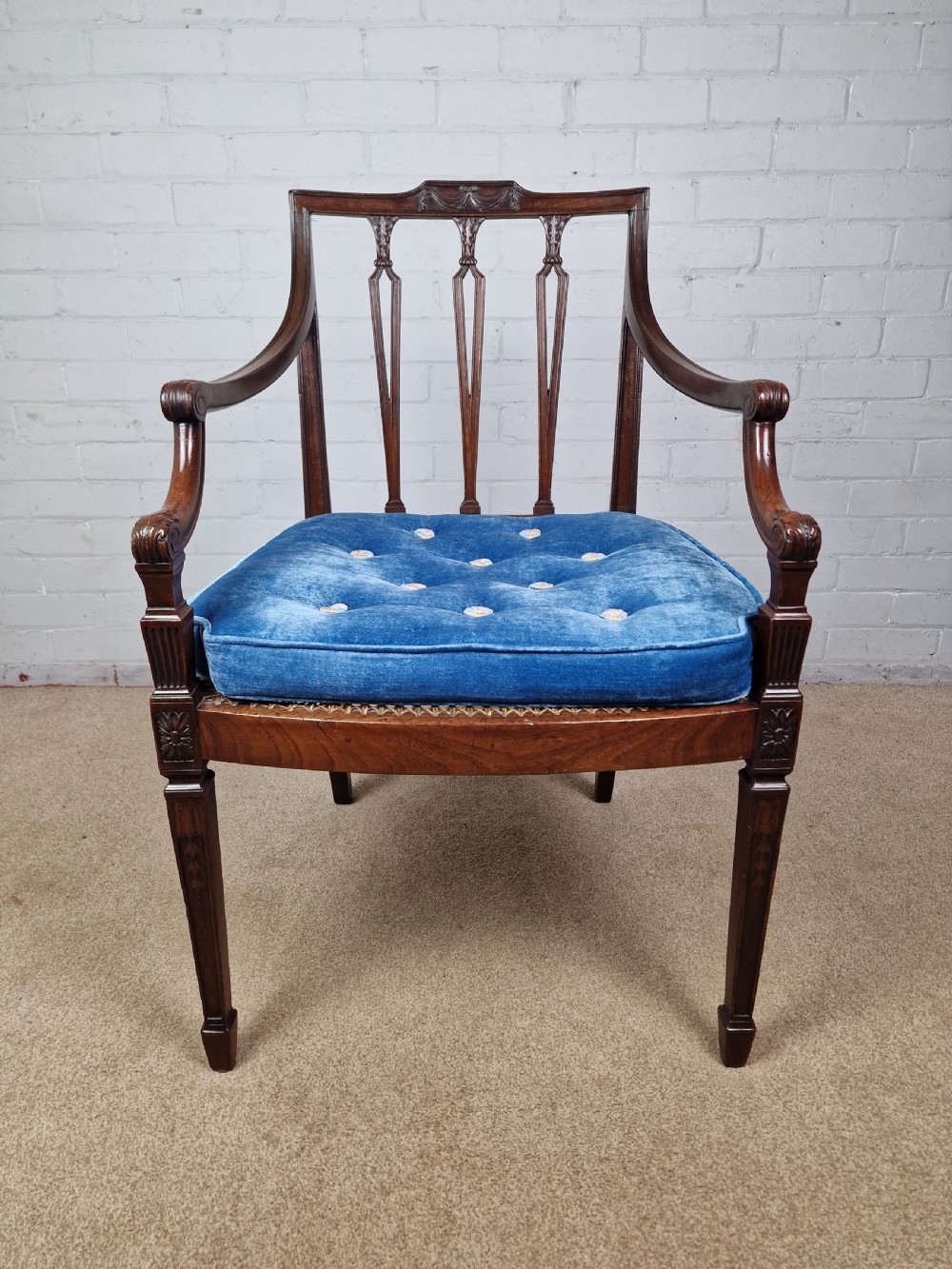 A Georgian mahogany open armchair featuring carved splats, curved arms, tapered fluted front legs, and a padded blue velvet cushion seat. View XI