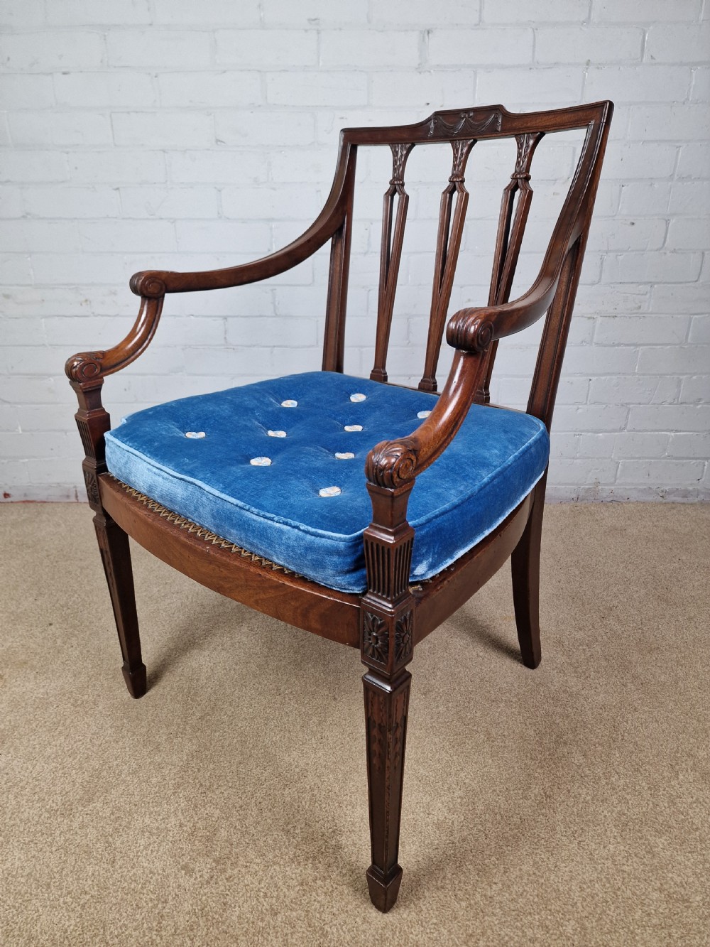 A Georgian mahogany open armchair featuring carved splats, curved arms, tapered fluted front legs, and a padded blue velvet cushion seat. View XIV