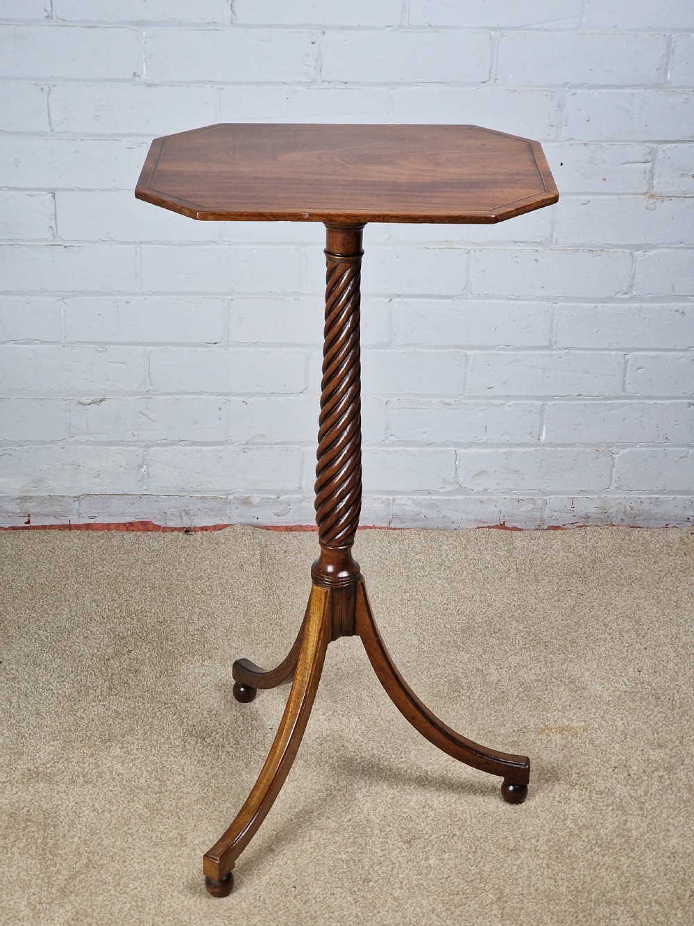 An early nineteenth-century Regency mahogany tripod table featuring an octagonal top with boxwood stringing, a spiral-turned stem, and downcurved tripod legs.