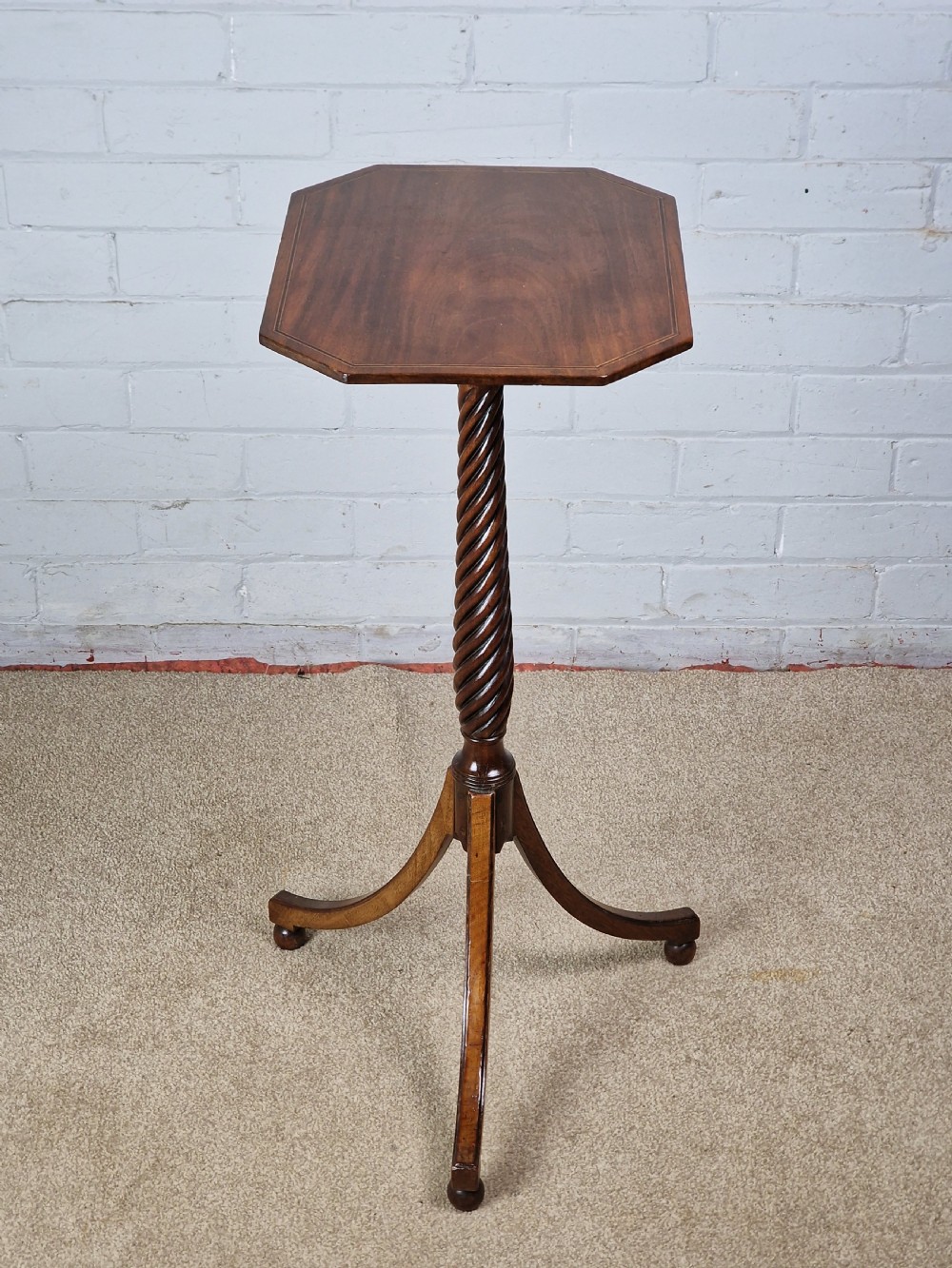 An early nineteenth-century Regency mahogany tripod table featuring an octagonal top with boxwood stringing, a spiral-turned stem, and downcurved tripod legs. View V
