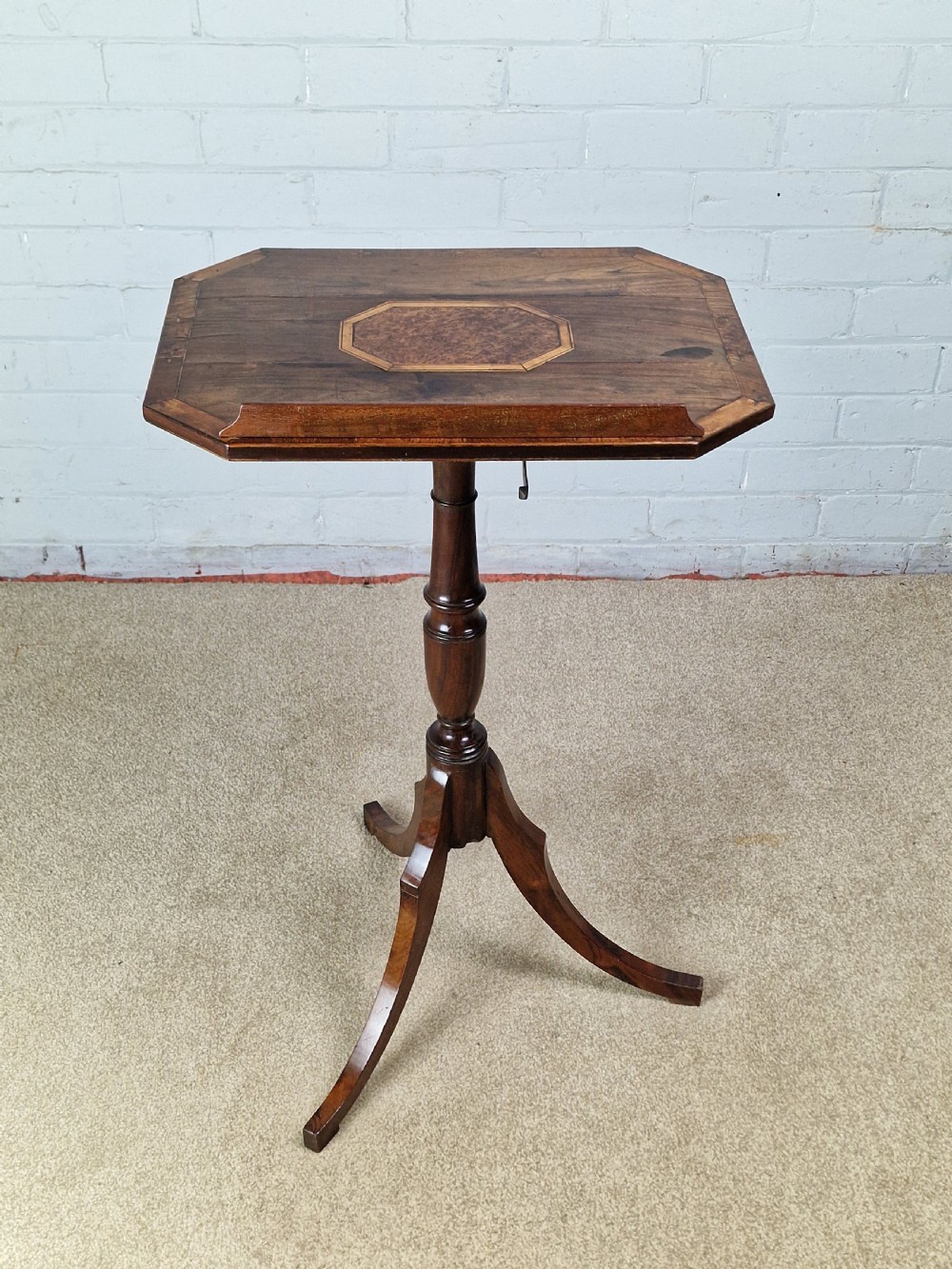 An early 19th-century Regency mahogany reading table featuring an octagonal inlaid tilt top with a raised book lip, supported by a turned column on tripod legs.