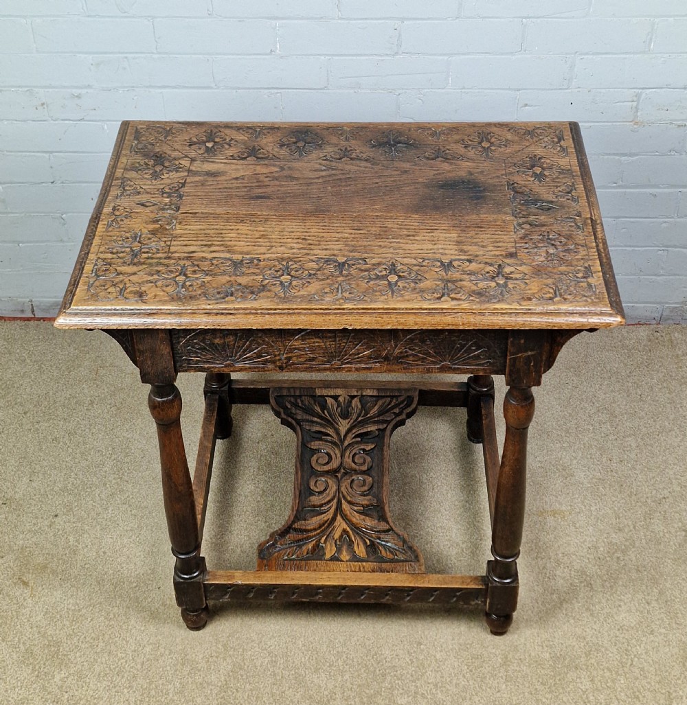 A late Victorian rectangular side table in carved brown oak, featuring a floral border top, lunette carved apron, turned legs, and a carved lower stretcher. View V