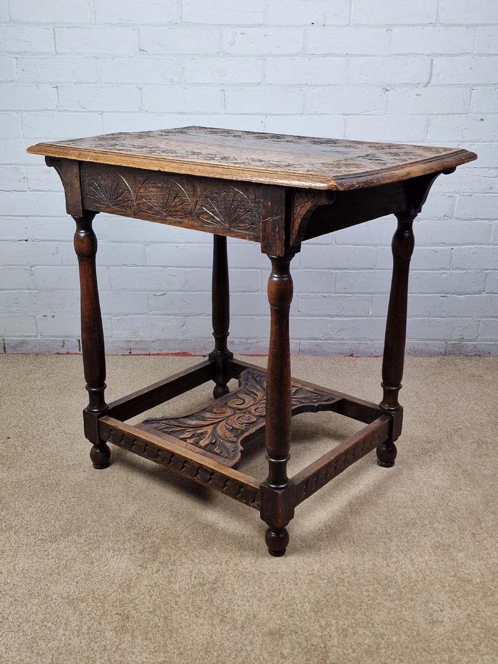 A late Victorian rectangular side table in carved brown oak, featuring a floral border top, lunette carved apron, turned legs, and a carved lower stretcher. View II