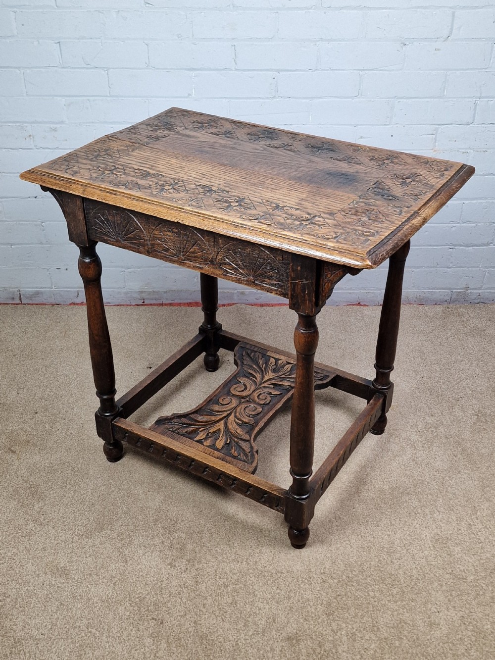 A late Victorian rectangular side table in carved brown oak, featuring a floral border top, lunette carved apron, turned legs, and a carved lower stretcher. View IV