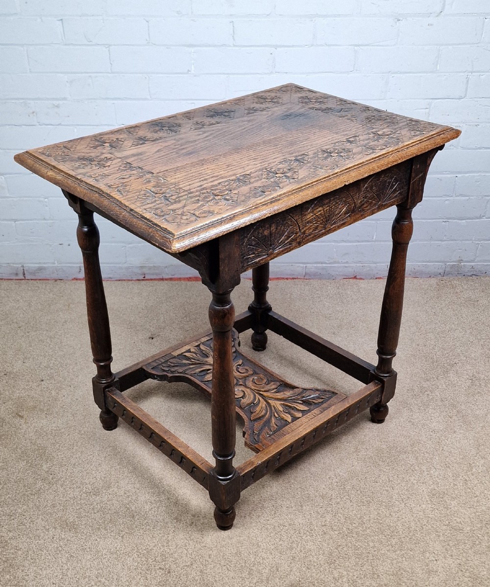 A late Victorian rectangular side table in carved brown oak, featuring a floral border top, lunette carved apron, turned legs, and a carved lower stretcher.