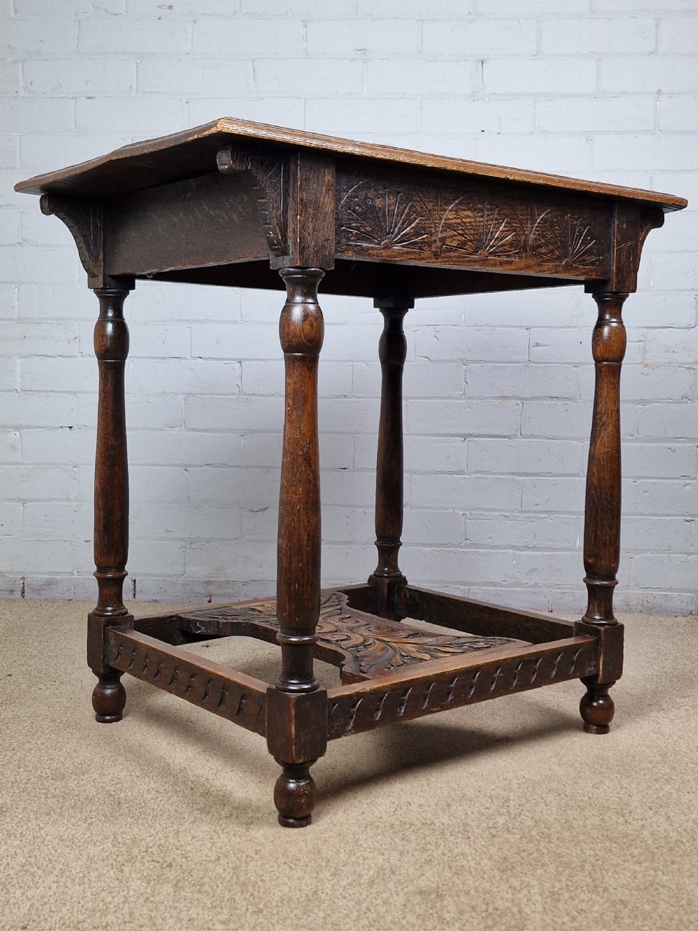 A late Victorian rectangular side table in carved brown oak, featuring a floral border top, lunette carved apron, turned legs, and a carved lower stretcher. View VI