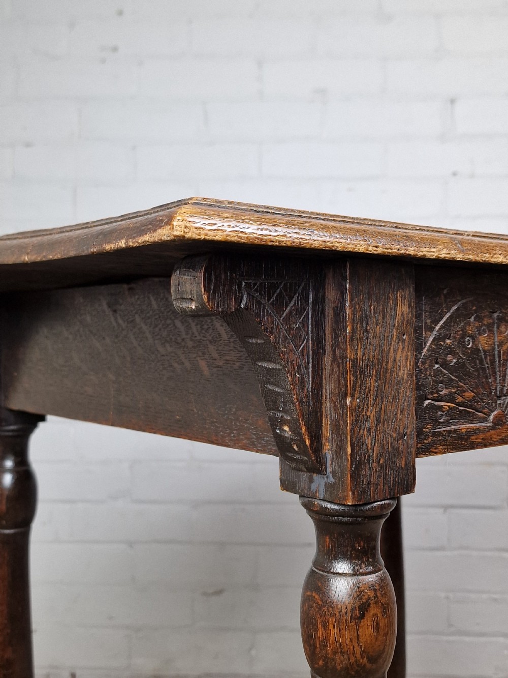 A late Victorian rectangular side table in carved brown oak, featuring a floral border top, lunette carved apron, turned legs, and a carved lower stretcher. View VII