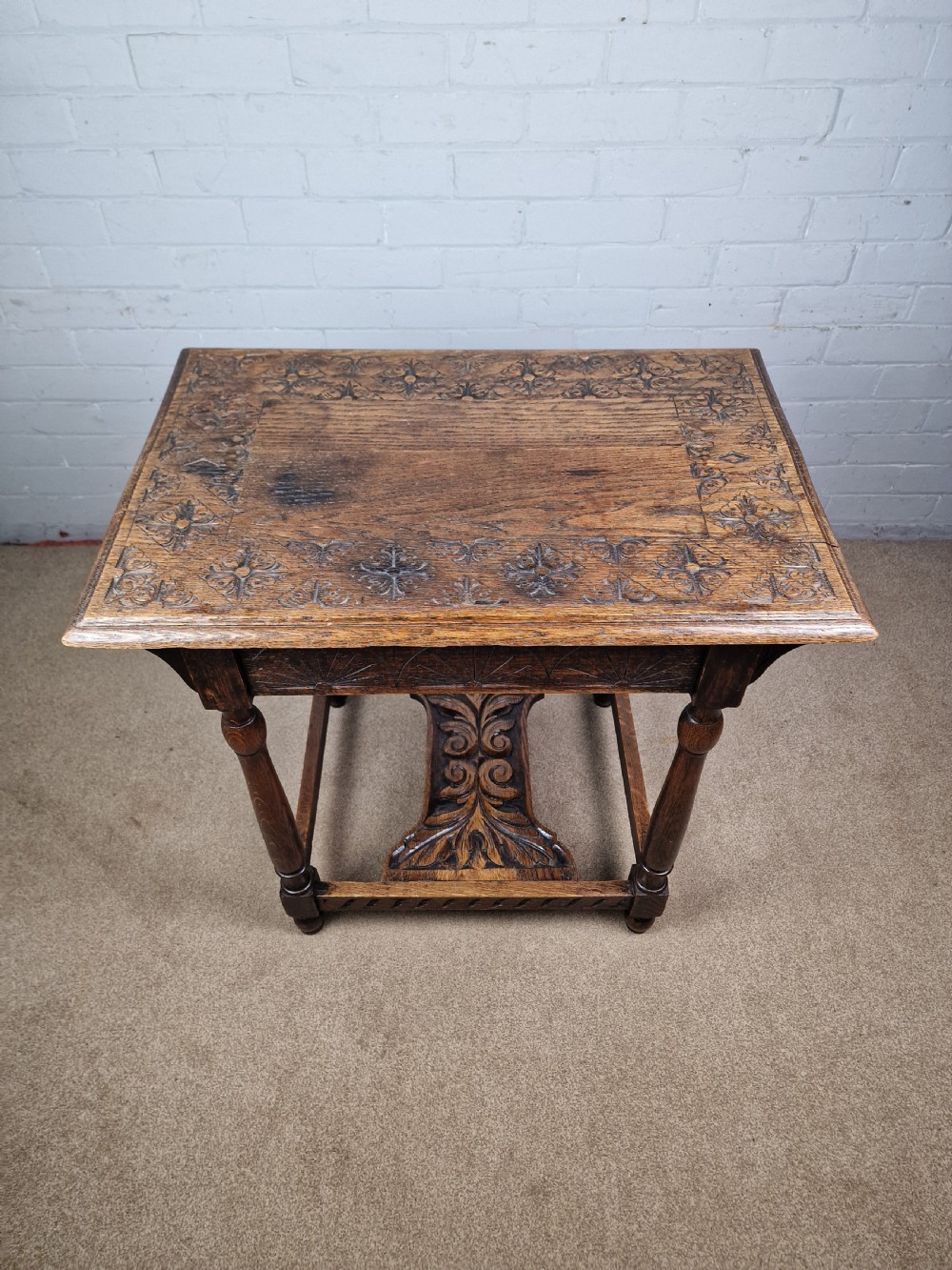 A late Victorian rectangular side table in carved brown oak, featuring a floral border top, lunette carved apron, turned legs, and a carved lower stretcher. View IX