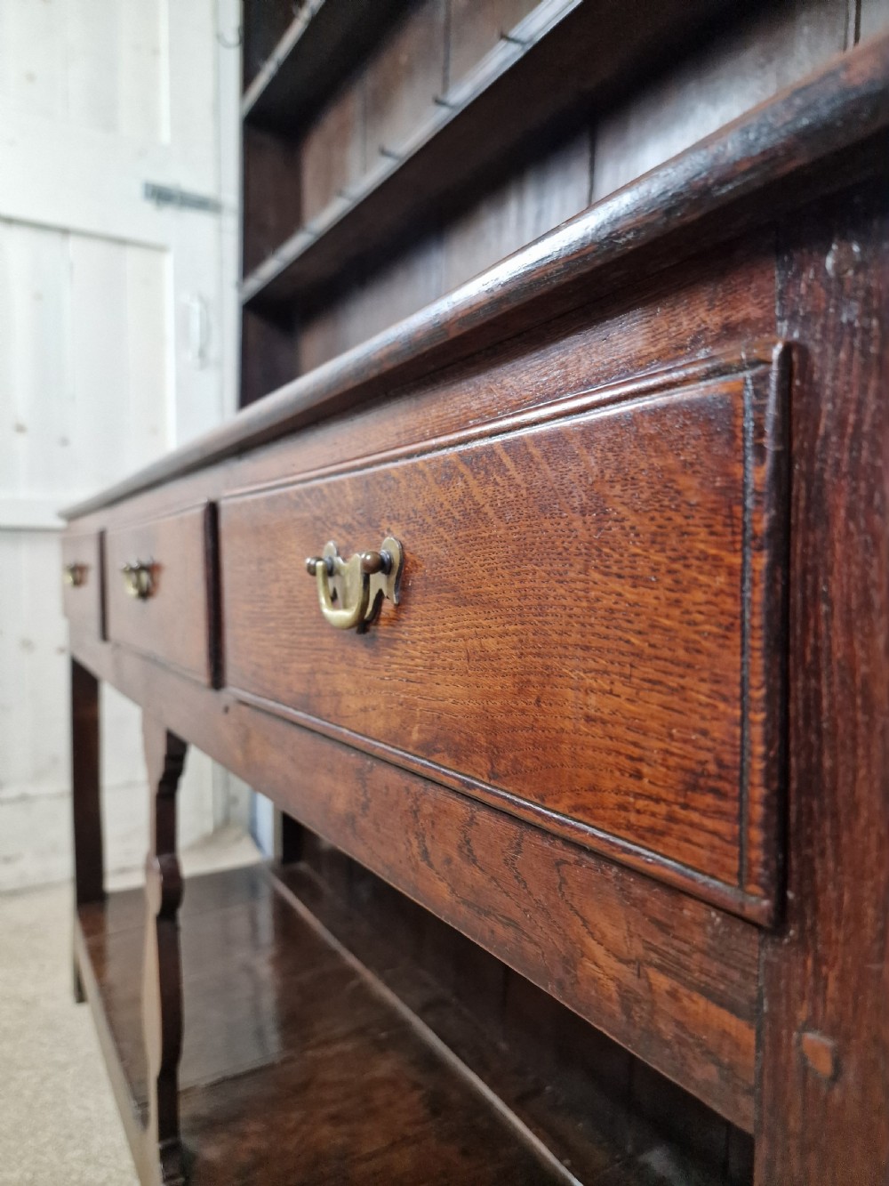 An 18th-century George II oak dresser featuring a top open plate rack above three frieze drawers and an open lower pot shelf. View II